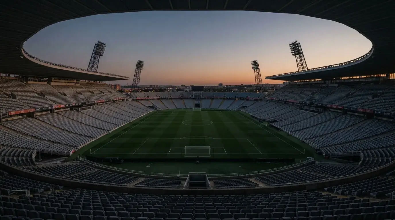 Een leeg voetbalstadion met lichtmasten bij schemering